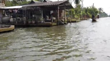 Bir kayıkçı tarafından kullanılan uzun kuyruklu tekne Bangkok, Tayland 'da bir kanal dolusu turistin yanından geçiyor.