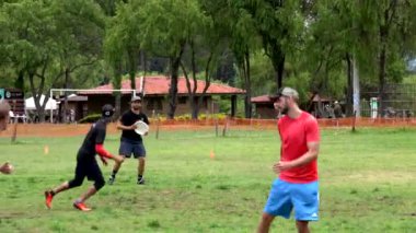 Parktaki frizbi oyununda geçen ve koşan sporcular takım çalışmasını ve rekabetçi ruhunu sergilediler.