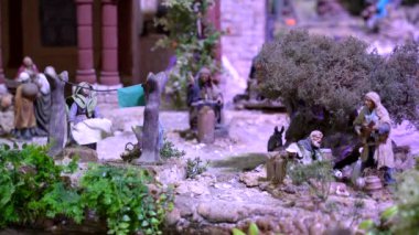 Diğer insanlar minyatür bir noel doğum sahnesinde günlük görevlerini yaparken kadınlar çamaşır ipine giysilerini asıyor.