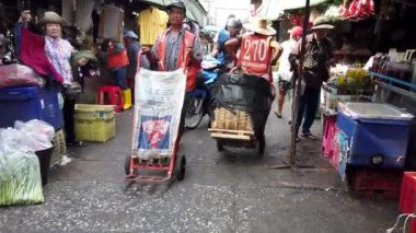 Bangkok, Tayland 'da dar bir sokak pazarını dolduran müşteriler ve satıcılar canlı bir ticaret ve kültür ortamı yaratıyorlar.
