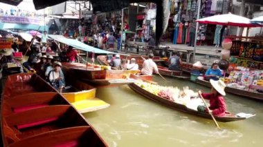 Tedarikçi, teknesini kalabalık bir kanaldan Bangkok, Tayland 'da yüzen bir markete doğru itiyor.