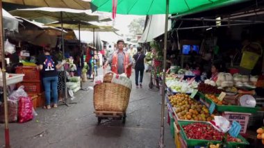 Bangkok 'taki hareketli açık hava pazarında turistler ve yerel halk yiyecek ve ürünlerle dolu canlı tezgahlarda geziniyorlar.