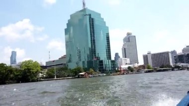 Sürat teknesi dalgalar yaratıyor, bu sırada Koyaya nehri boyunca ilerleyip Bangkok 'taki diğer tekne ve otelleri geçiyor.