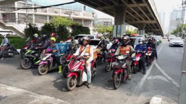 Yiyecek teslimatçıları da dahil olmak üzere motosikletliler Bangkok, Tayland 'da yoğun bir kavşakta bekliyorlar.