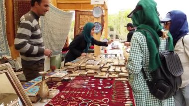 İranlı satıcı, İsfahan, İran 'da hareketli bir pazar yerinde müşterilere mücevher gösteriyor.
