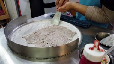 Sokak satıcısı soğuk tabakta çikolatalı kurabiye hamurlu dondurma hazırlıyor, lezzetli bir tatlı sergiliyor.