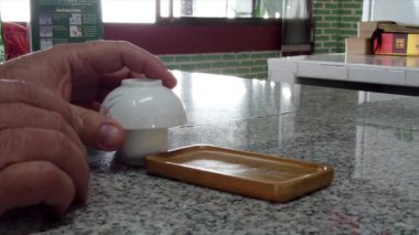 Çay seremonisi sunucusu, çay fincanını tepside ters çeviriyor, geleneksel içecek hazırlama ritüelini sergiliyor.