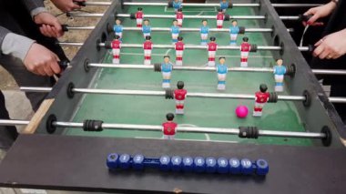 İnsanlar, mavi ve kırmızı oyuncuların yer aldığı, eğlenceli ve rekabetçi ruhların gösterildiği langırt masası oyununa girişiyor.