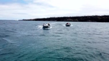 Turist ve rehber taşıyan iki şişme bot Galapagos adasından bir yolcu gemisine dönüyorlar.