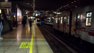 Metro trenleri bir istasyon platformuna ulaşır, yolcular şehir merkezinde yolculuk için bekler ve hazırlanırlar.