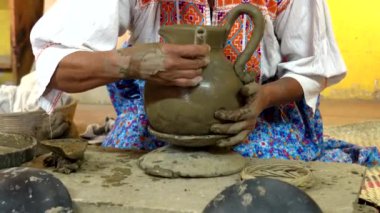Bir kil sürahiyi bir aletle süslemek, kabartmalı noktalar ve çizgilerden oluşan karmaşık bir şablon yaratır.