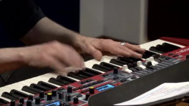 Yakın çekim, canlı bir performans sırasında canlı bir klavye sentezleyicisini ustalıkla çalan bir müzisyenin ellerini yakalar.