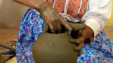 Geleneksel giysiler içindeki Potter, Oaxaca 'daki kil bir geminin tepesini şekillendiriyor.