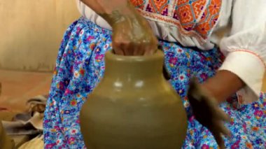 Potter ustalıkla bir kil atıcının en üst katmanını oluşturuyor, geleneksel teknikler ve zanaatkarlık sergiliyor.
