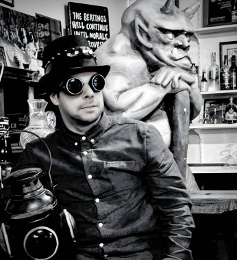 Stylish individual in steampunk fashion posing with a gargoyle figure in a vintage setting clipart