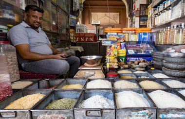 Yerli dükkan sahibi dükkanında bir dizi tahıl ve baharatla çevrili.