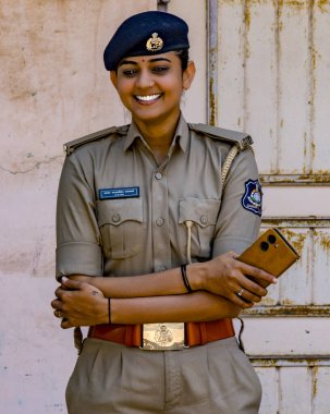 Resmi giyinmiş, gururlu ve neşeli bayan polis memuru kendine güveniyor.