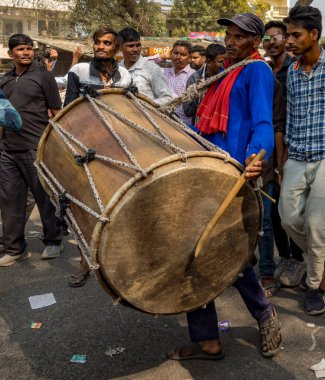 Hintli bir adam festival sırasında büyük bir davul çalar.