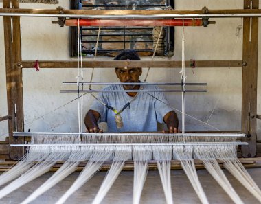 Odaklanmış zanaatkar bir dokuma tezgahı üzerinde çalışarak, ustalıkla tekstil yaratıyor.