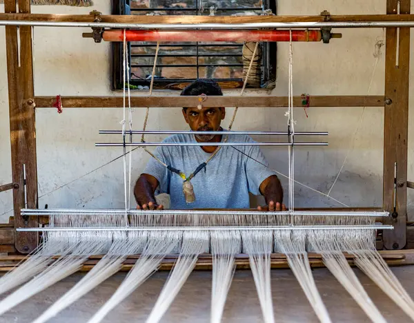 Odaklanmış zanaatkar bir dokuma tezgahı üzerinde çalışarak, ustalıkla tekstil yaratıyor.