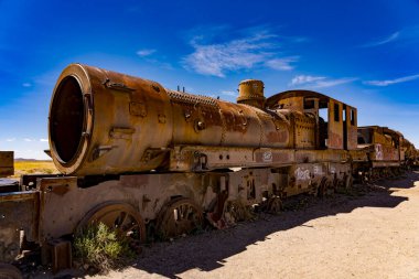 Bolivya, Uyuni yakınlarındaki tren mezarlığının çöl manzarasında çürüyen eski paslı buhar treni.