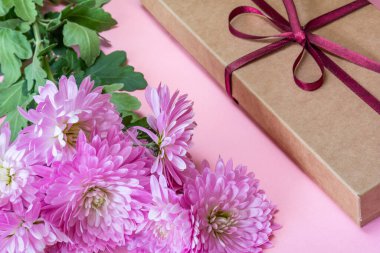 Pembe kasımpatı buketi ve pembe arka planda hediye kutusu.