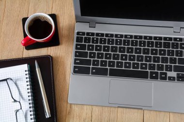 Dizüstü bilgisayar, kalem ve bir fincan kahveyle ahşap masa.