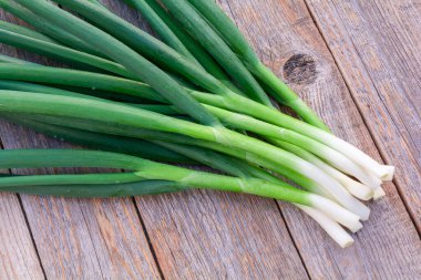 Eski ahşap bir masadaki tüy üzerinde taze soğanlar.