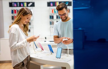 Teknoloji alışverişi dijital cihaz konsepti. Mobil dükkanından yeni bir akıllı telefon alan mutlu gençler.