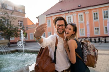 Mutlu seyahat eden genç çift selfie çekiyor, tatilde eğleniyor. İnsanlar teknoloji mutluluk kavramı.