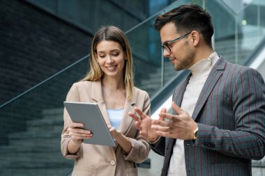 Başarılı genç iş adamları, tasarımcılar konuşuyor, modern iş binası önünde birlikte çalışıyorlar.