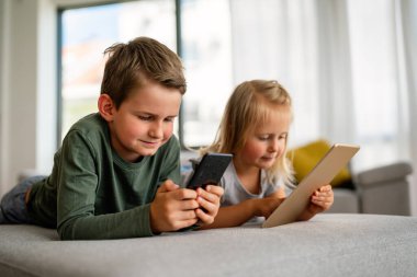 Küçük kız ve oğlan video izliyor ya da dijital cihaz tabletlerinde oyun oynuyorlar, akıllı telefon. Çocuklar dijital bağımlılık kavramı.