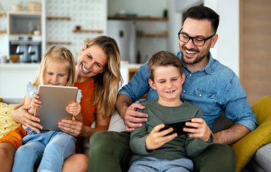 Happy young family having fun time at home. Parents with children using digital device. Education parenting happiness concept.