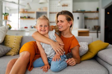 Sevgi dolu bir aile. Genç anne ve kızı çocuk evde oynaşıyor ve sarılıyorlar.