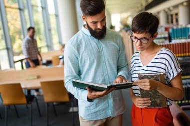 Bir üniversite kütüphanesinde birlikte çalışan mutlu bir öğrenci grubu. Eğitim insanları takım çalışması kavramı.