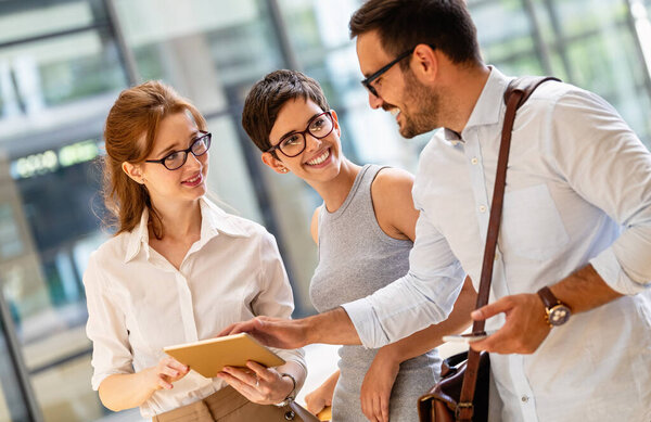Happy business colleagues in modern office working together and using tablet