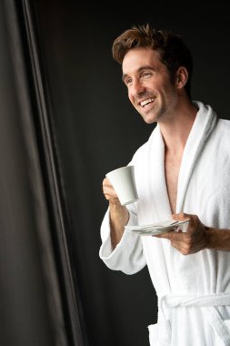 Yakışıklı genç adam sabahları evde kahve içiyor.