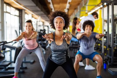 Çok ırklı bir grup insan spor salonunda antrenman yapıyor. Antrenör ve spor fitness sınıfında egzersiz yapan sağlıklı insanlar.