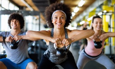Spor salonunda spor yapan formda insanlardan oluşan bir grup. Spor salonunda birlikte egzersiz yapan çok ırklı arkadaşlar..