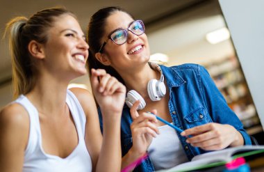 Kütüphanede kitaplarla çalışan mutlu genç üniversite öğrencileri. Üniversitede bir grup çok ırklı insan.