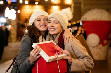 Noel hediyelerini değiş tokuş eden iki mutlu kadının portresi. Tatilciler Noel 'de alışveriş yapar. Mutluluk kavramı.