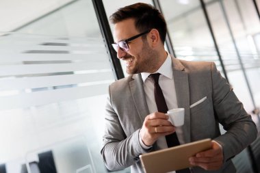 Şirket ofisinde tabletle çalışan genç ve mutlu bir iş adamı. İş adamları konsepti