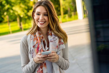 Güzel genç bir iş, dışarıda cep telefonu kullanan öğrenci bir kadın. İnsanlar iletişim teknolojisi kavramı.