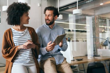 Gülümseyen çeşitli meslektaşlar toplantı odasında toplanmış mali istatistikleri tartışıyorlar. Mutlu çok ırklı iş arkadaşları ofis toplantılarında işbirliği yaparken eğleniyorlar. Takım çalışması konsepti.