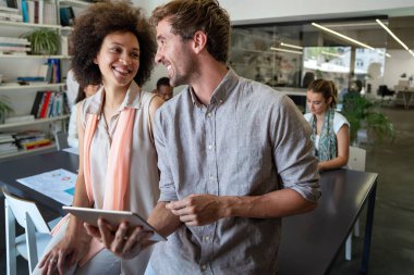 Gülümseyen çeşitli meslektaşlar toplantı odasında toplanmış mali istatistikleri tartışıyorlar. Mutlu çok ırklı iş arkadaşları ofis toplantılarında işbirliği yaparken eğleniyorlar. Takım çalışması konsepti.