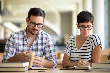 Kütüphanede kitaplarla çalışan mutlu genç üniversite öğrencileri. Üniversitede bir grup çok ırklı insan