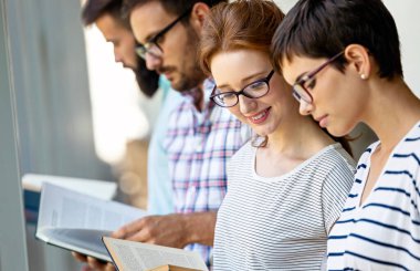 Bir üniversite kütüphanesinde birlikte çalışan mutlu bir öğrenci grubu. Eğitim insanları takım çalışması kavramı.