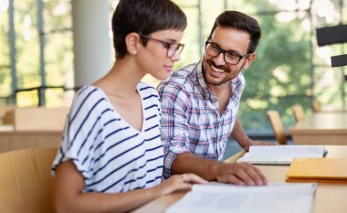 Bir üniversite kütüphanesinde birlikte çalışan mutlu bir öğrenci grubu. Eğitim insanları takım çalışması kavramı.