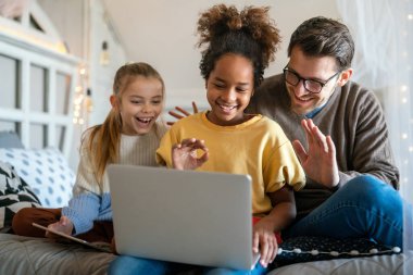Halk ailesi ve teknoloji kavramı. Çok ırklı çocukları olan mutlu bir baba görüntülü sohbetle eğleniyor.