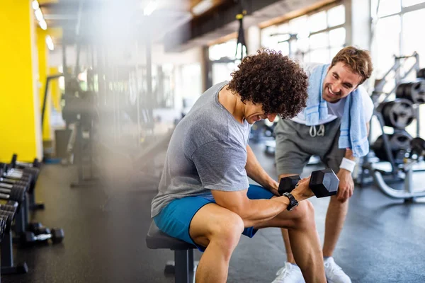 Fit young man working out in gym with personal trainer to stay healthy. Sport, people concept